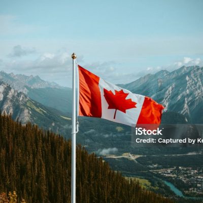 Canadian flag with mountain and small town views in summer